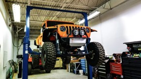 A Jeep truck on a lift at an auto shop