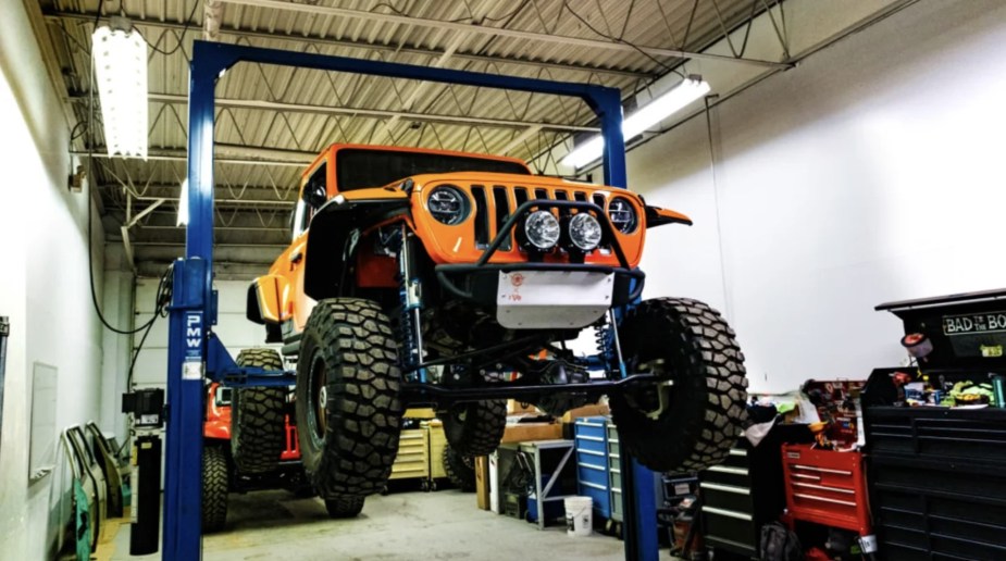 A Jeep truck on a lift at an auto shop