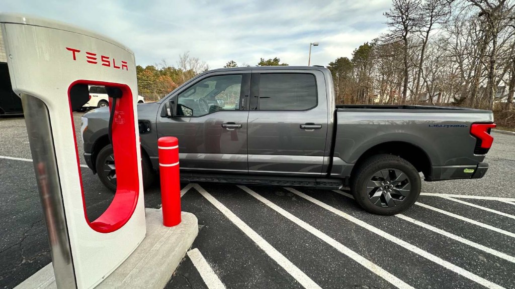 Ford F-150 Lightning Next to a Tesal Supercharger because the charging cable isn't long enough to reache the F-150 Lightning charge port.