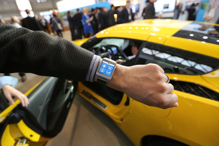 Smartwatch with Onstar app in front of a Corvette
