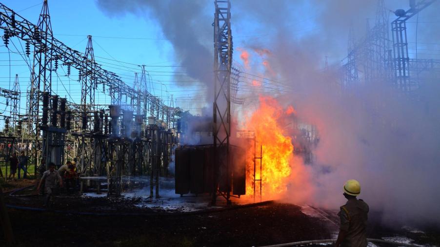 Huge orange flames engulfing a power transformer in a yard of power lines