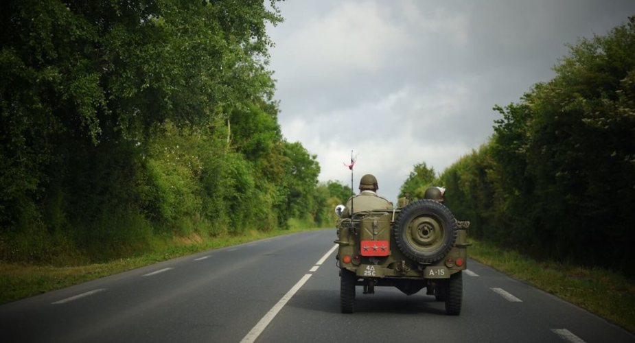 A WWII-era Willys MB drives with its windshield down.
