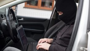 Auto theft in progress as a man hacks a sedan.