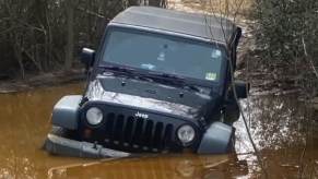 A Jeep Wrangler JK stuck in a boggy trail.