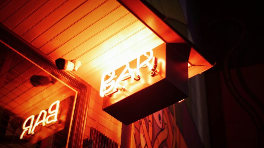 The neon "bar" sign by a bar's mirror.