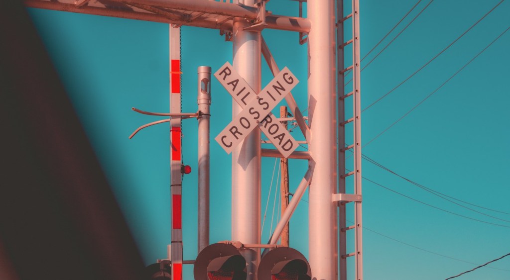 The crossed railroad crossing sign and red stop lights at a track.