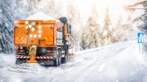 Dump truck spreads salt on a highway road during a winter snow storm