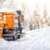 Dump truck spreads salt on a highway road during a winter snow storm