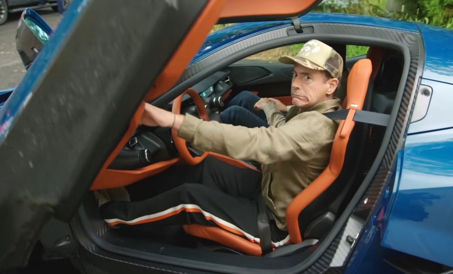 Robert Downey Jr. closes the scissor door of an exotic sports car.