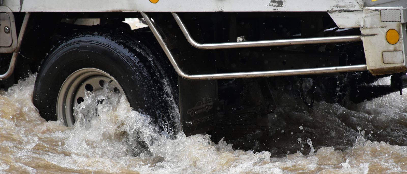 The wheels of a semi truck crashing in to a pond.