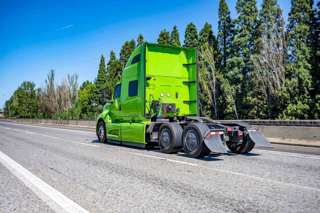 A bright-green semi truck tractor unit on the highway.