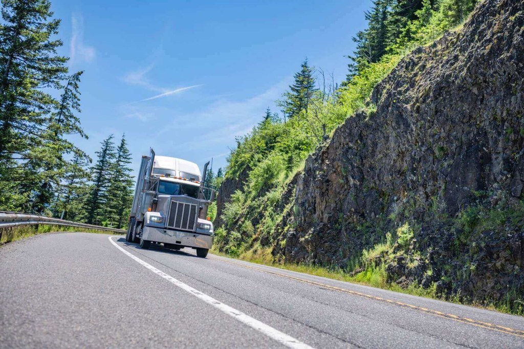 A semi truck drives around a corner.