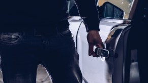 The hand of a thief opening the door of a silver Chevy Camaro