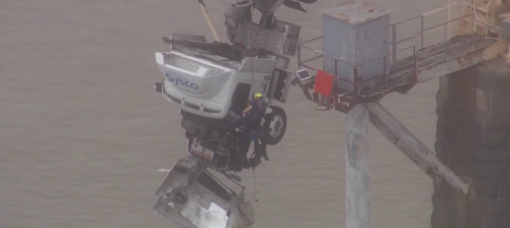 A firefighter rescues a truck driver from a semi-truck crash.