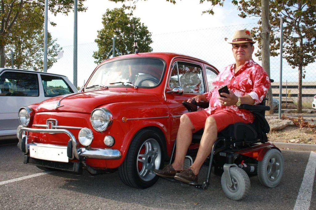 An wheelchair-bound enthusiast without the use of his legs shows off his classic car. 