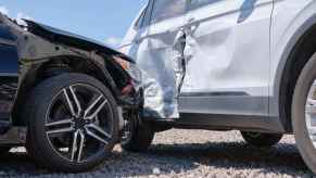 A car accident with a white SUV right rear side view after a black car crashes into it close view