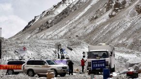 Several SUVs and a commercial truck parked at Everest Base Camp North in Tibet