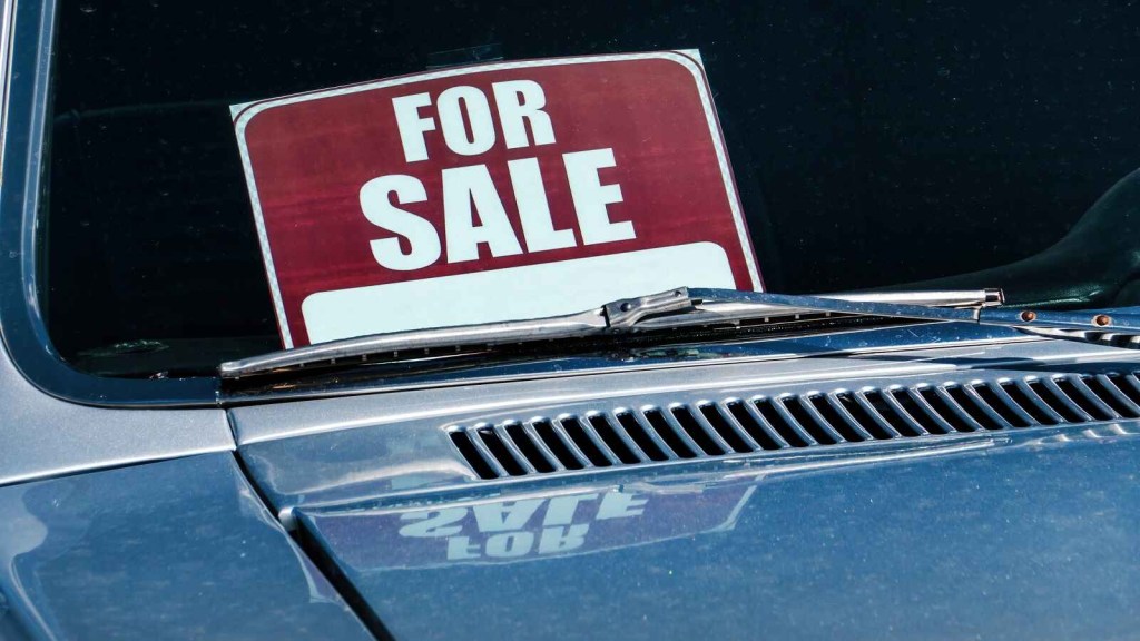 A "for sale" sign shown in a blue used car windshield in close angle view