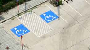 Two handicapped parking spots in a parking lot shown from above blue painted boxes with stick figure in wheel chair