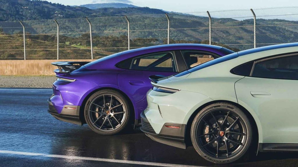 The right rear profile rear halves of two Porsche Taycan Turbo GTs, one with the Weissach track package, parked on a track