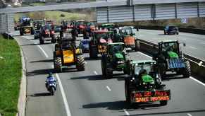 Famers drive tractors down the A63 highway in southwestern France blue, green, yellow tractors take up the road