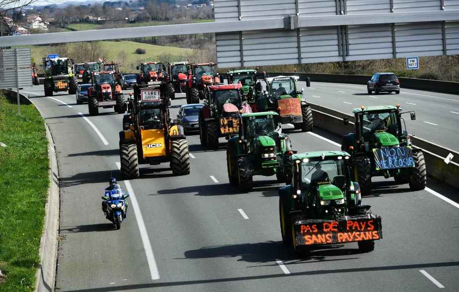 Famers drive tractors down the A63 highway in southwestern France blue, green, yellow tractors take up the road