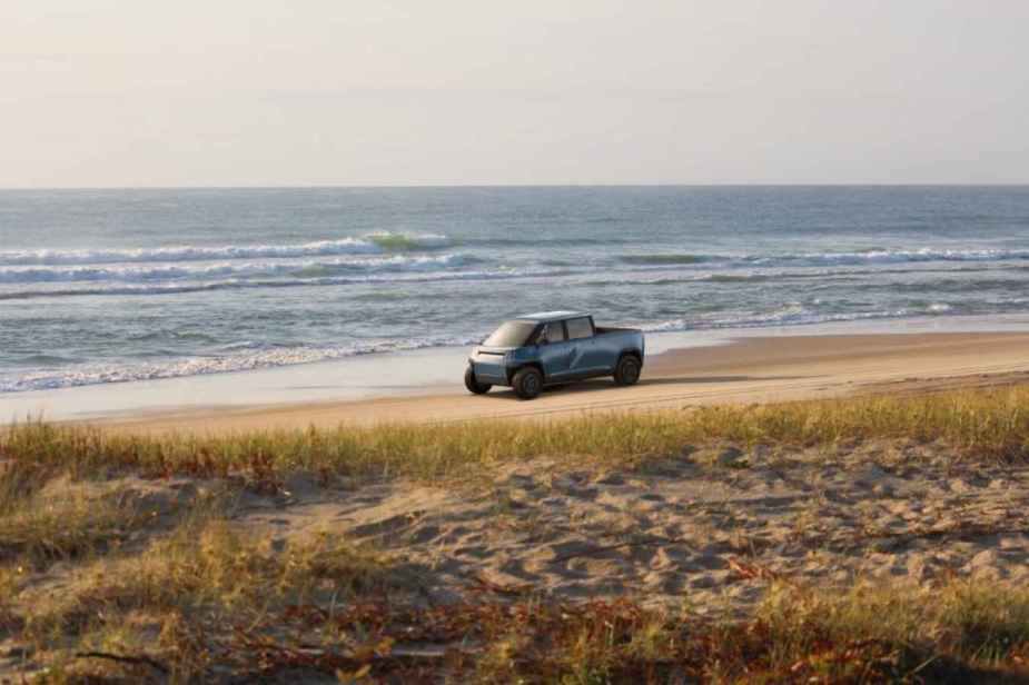 A retendering of a Telo subcompact AWD EV pickup driving down a beach midground right profile view