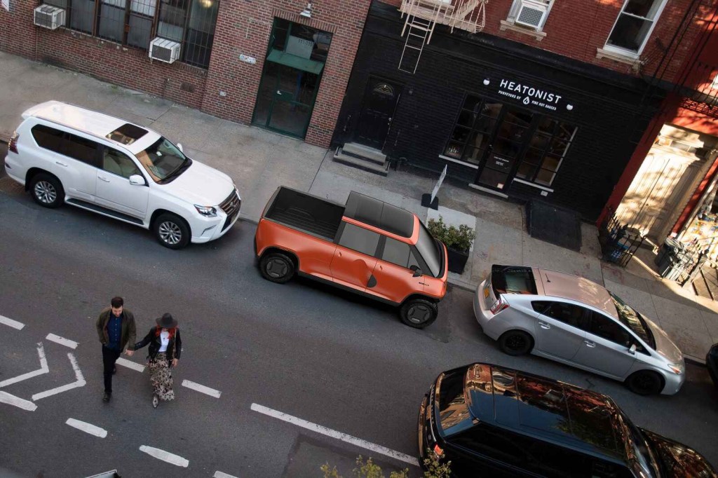 A concept rendering of a metallic orange Telo subcompact EV truck parallel parked on a city street overhead right profile view