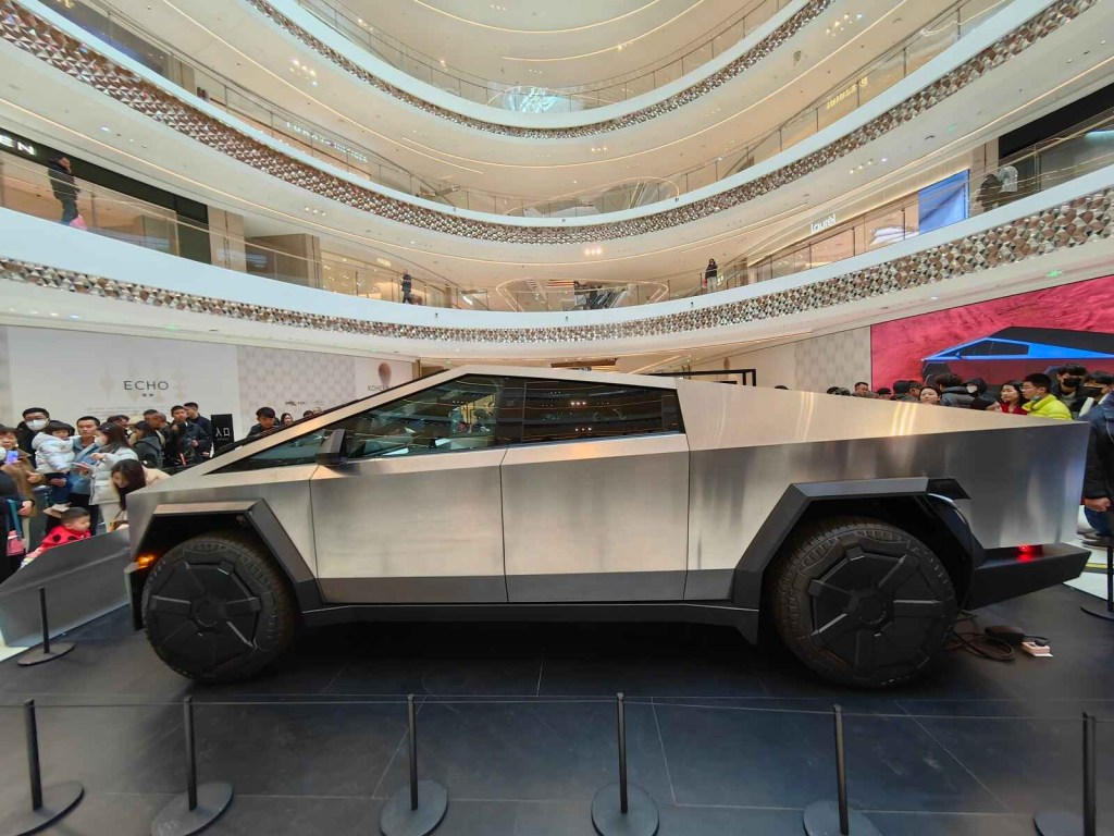 A Tesla Cybertruck is parked inside a mall in full left profile view