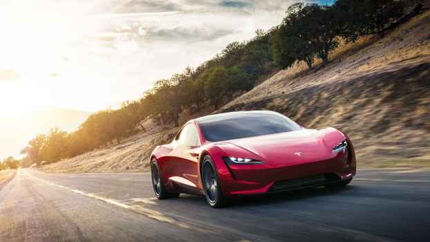 A red Tesla Roadster shown driving towards the viewer in right front angle view