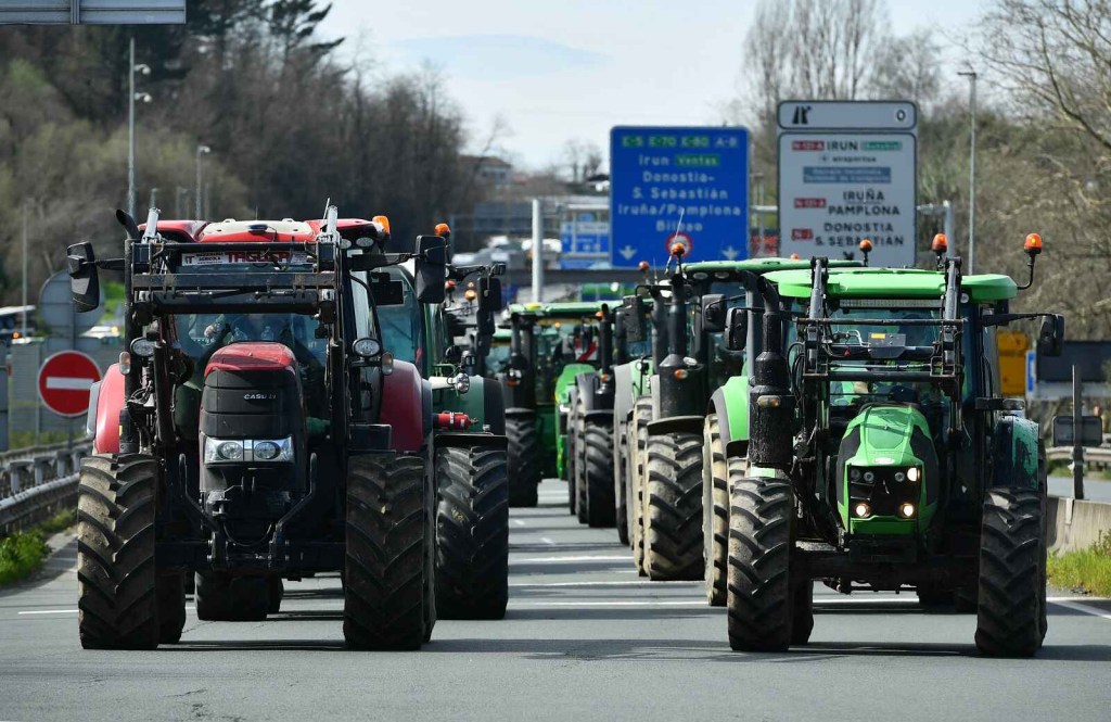 Spanish farmers drive tractors to block the border with France in protest of EU environmental initiatives two lines of tractors take up the roadway