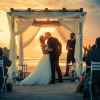 A bride and groom kiss after their beach wedding ceremony sunset