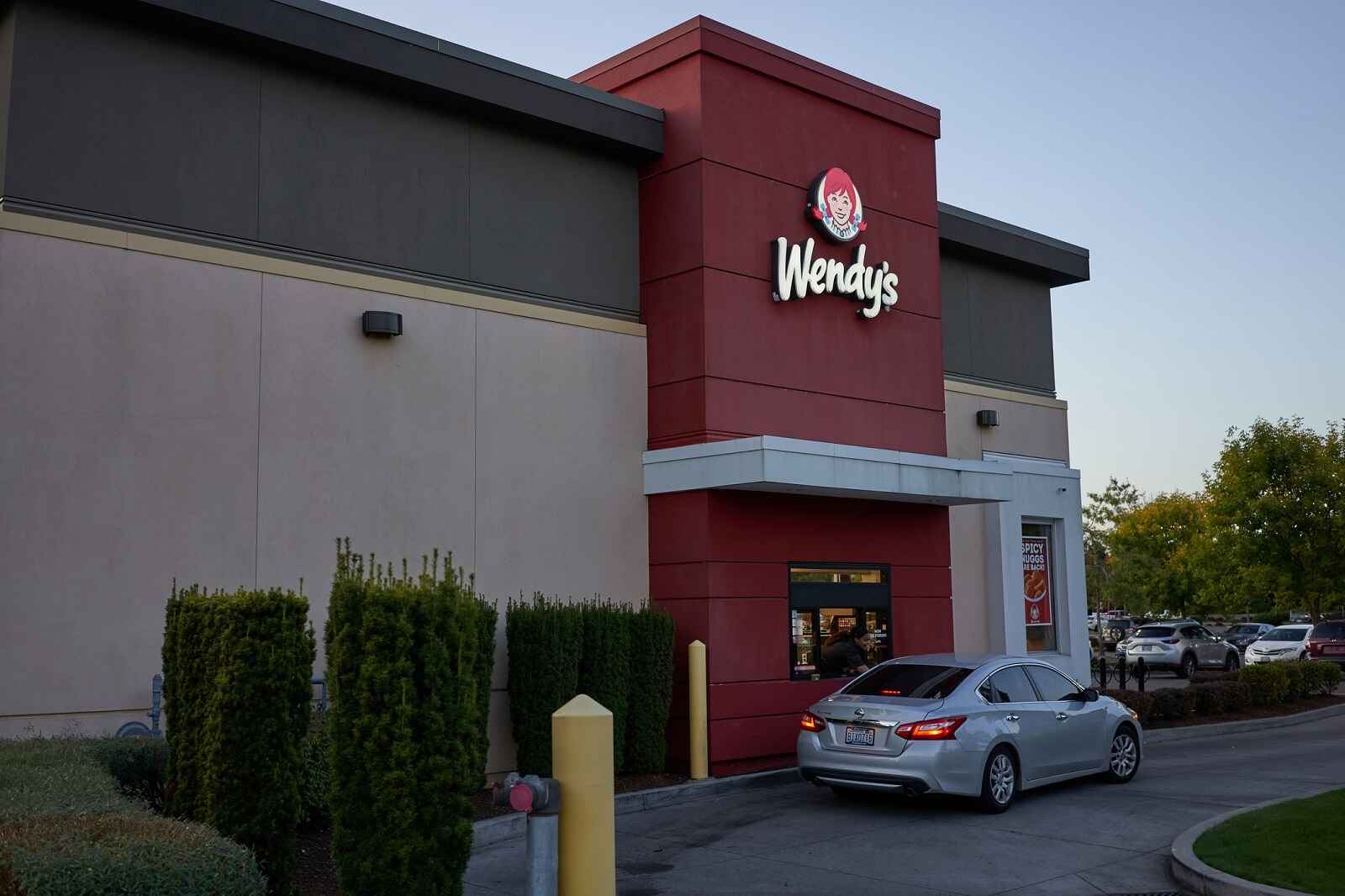 A silver sedan parked at a Wendy's drive-thru window