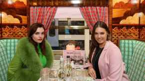 Charli Howard and Amber Le Bon sit in the British train carriage redesigned by Wes Anderson