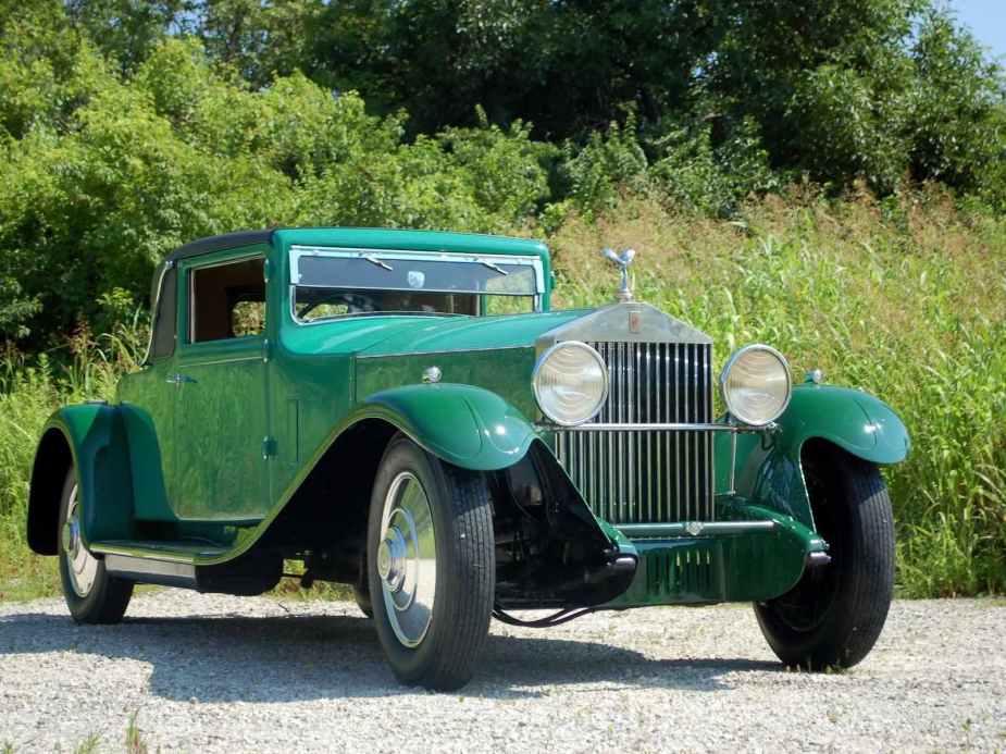 Kelly Green 1929 Rolls Royce coupe parked in front of trees.