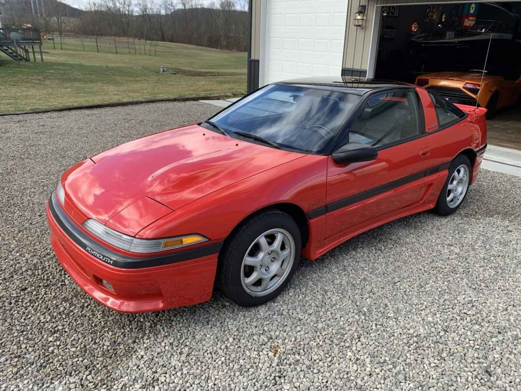 A red 1990 Plymouth Laser parked in gravel at left front angle view