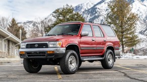 A red 1993 Toyota 4Runner parked in left front angle view with snow-covered mountains in the background