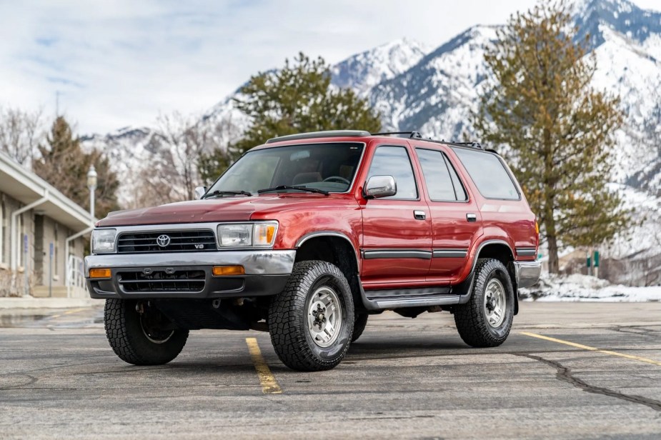 A red 1993 Toyota 4Runner parked in left front angle view with snow-covered mountains in the background