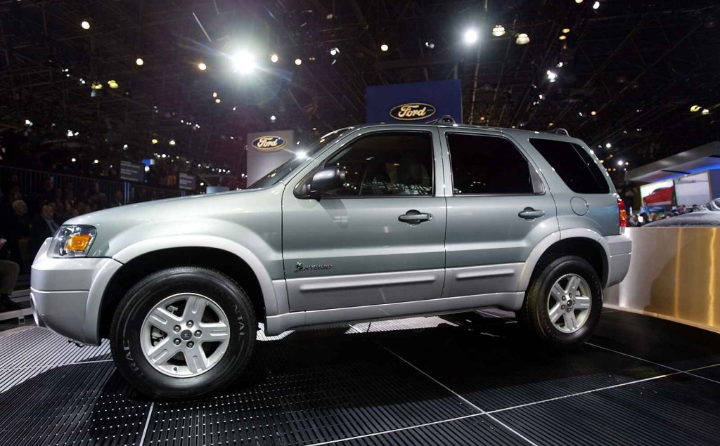 A silver 2005 Ford Escape Hybrid is shown on stage at an auto show unveiling