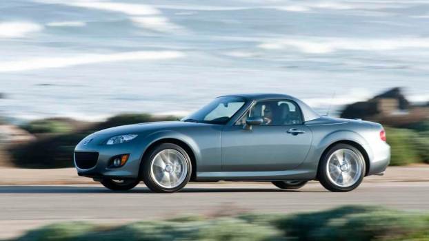 An NC Mazda MX-5 Miata shows off its hardtop convertible construction on the road.