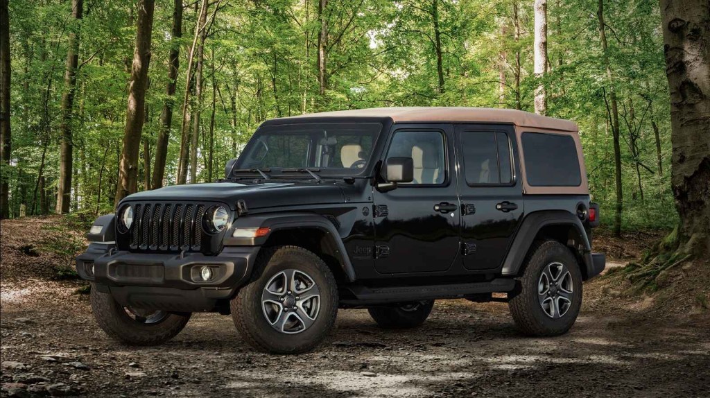 A 2020 Jeep Wrangler Black & Tan Edition parked in the woods in left front profile angle view