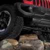 The right front underside corner of a red 2020 Jeep Wrangler Rubicon climbing rocks in close view