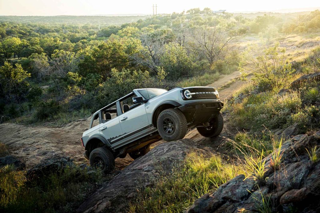 A 2021 Ford Bronco four-door SUV climbing rocks off-trail in right profile view