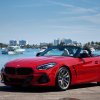 Red 2024 BMW Z4 parked by a marina.