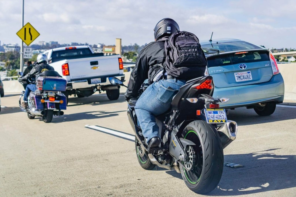A pair of riders about to ride between slow traffic on a sportbike and a bagger.