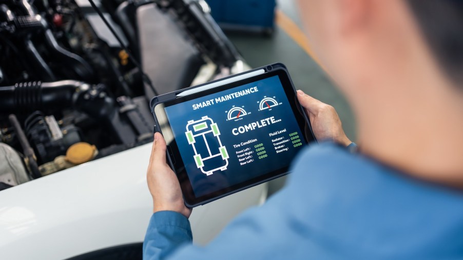 Technician uses a tablet computer to read the onboard diagnostics OBD II check engine codes of a car