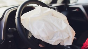 A white crumpled airbag sticking out of a steering wheel center.
