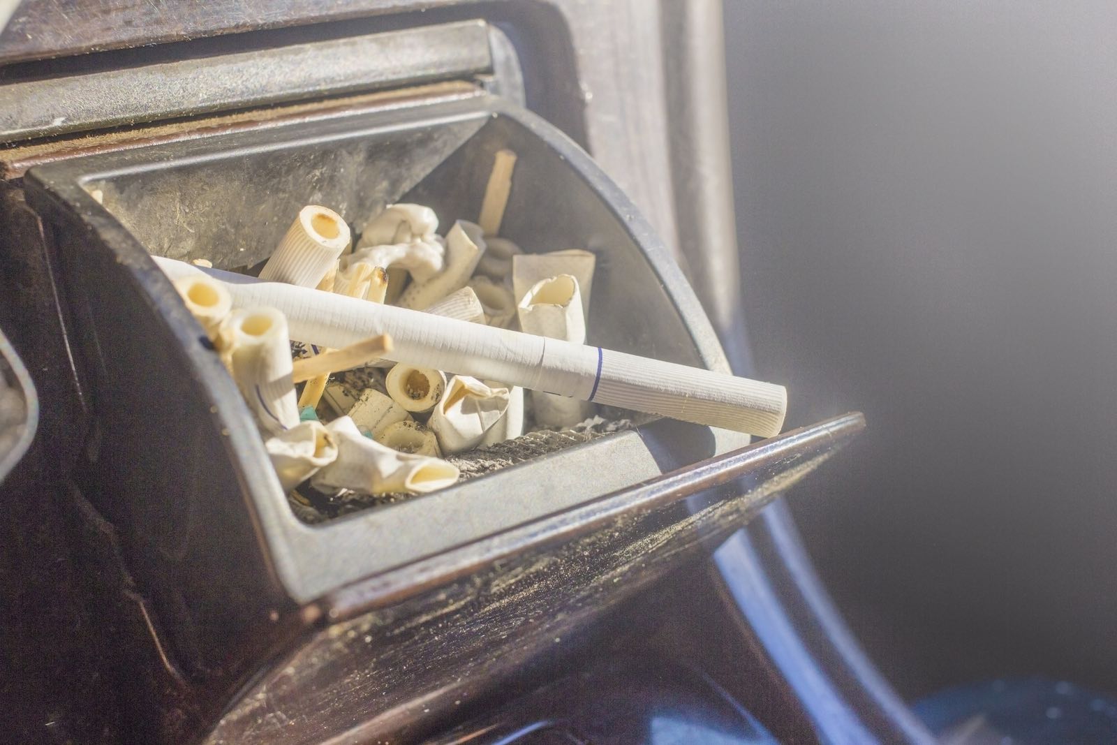 two cigarettes in an ashtray Ashtray. Dirty black ceramic ashtray with a cigarette, full of smokes  cigarettes. Isolated on a white background. Stock Photo