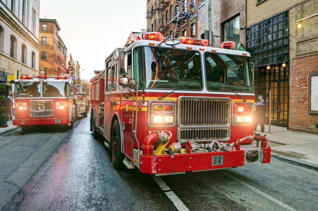 A set of fire engines on the street hold water for firefighting.