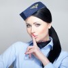 A young flight attendant holds her finger to her lips.